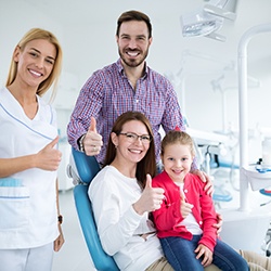 Happy parents posing with their child in dental office