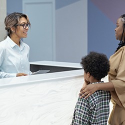 Parent and child standing at dental office front desk