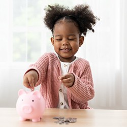 Child putting coins into her piggy bank