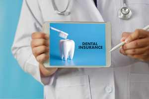 Dentist pointing to tablet that says “Dental Insurance”