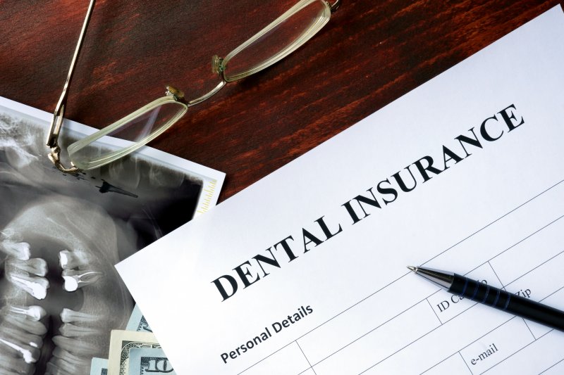 A dental insurance form laying on a brown, wooden desk